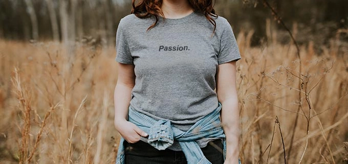 Eine Frau trägt ein bedrucktes T-Shirt mit Logo im Freien. Solch ein individuelles T-Shirt hilft Fitnessstudios neue Mitglieder zu gewinnen.